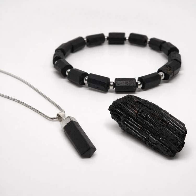 Zestaw ochronny z czarnego turmalinu – zbliżenie na naszyjnik z grotem, bransoletkę i surowy kamień.