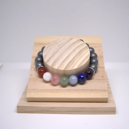 Bransoletka czakralna z Hematytem na drewnianej podstawce, z kamieniami czakr wspierającymi uziemienie i harmonizację energii.