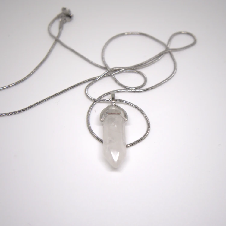 Zbliżenie naszyjnika z Kryształu Górskiego na srebrnym łańcuszku, elegancki grot kamienny na jasnym tle do sklepu internetowego.